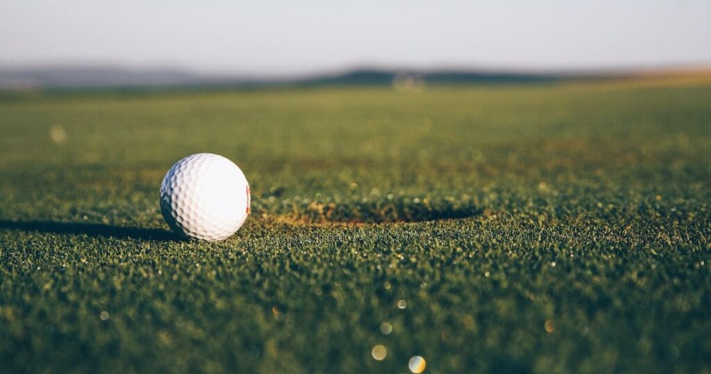 A golf ball rolling towards the cup on a green.