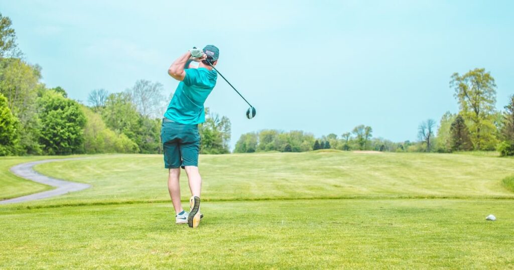 A golfer hitting a tee shot and focusing on not slicing his driver and land it in the fairway