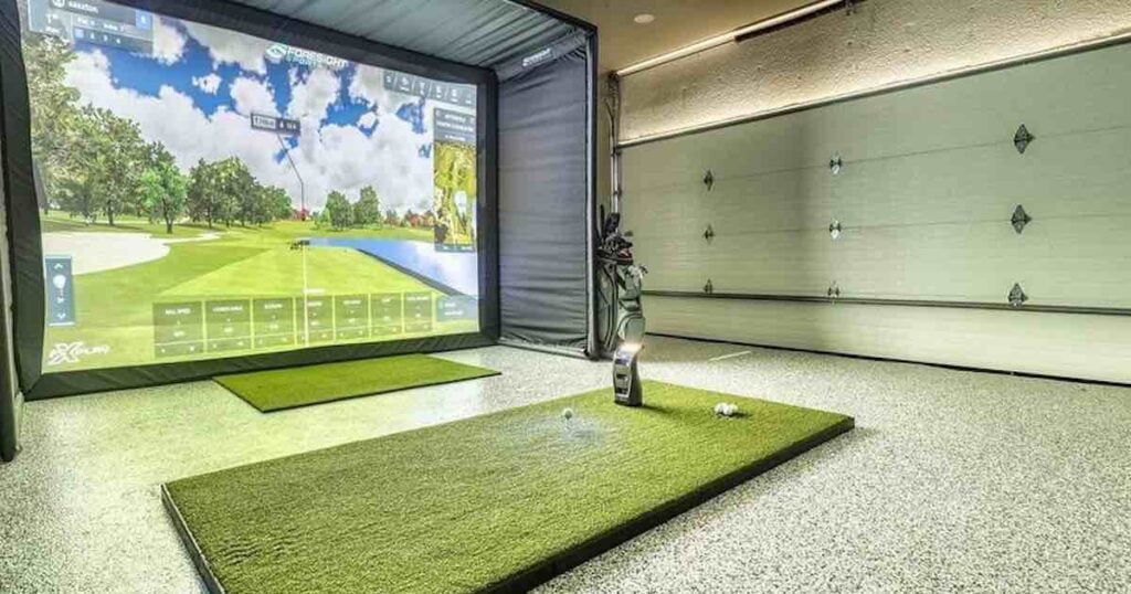 a home golf simulator set up in a a garage along with a mat and projection screen.