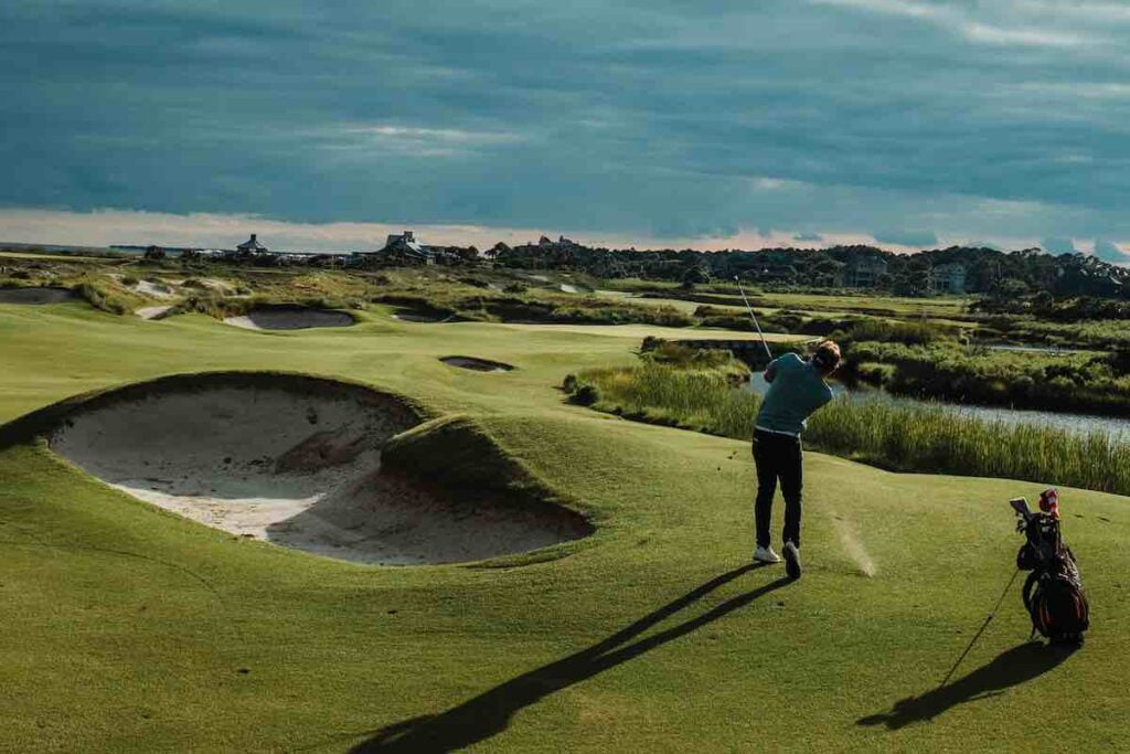 Golfer on a scenic golf course hitting a 52 degree gap wedge for an approach shot.