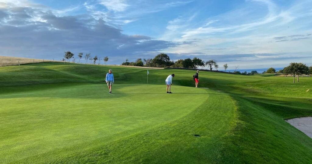 Golfers of various skill levels putting on a scenic golf green. The handicap in golf allows these players to all compete together.