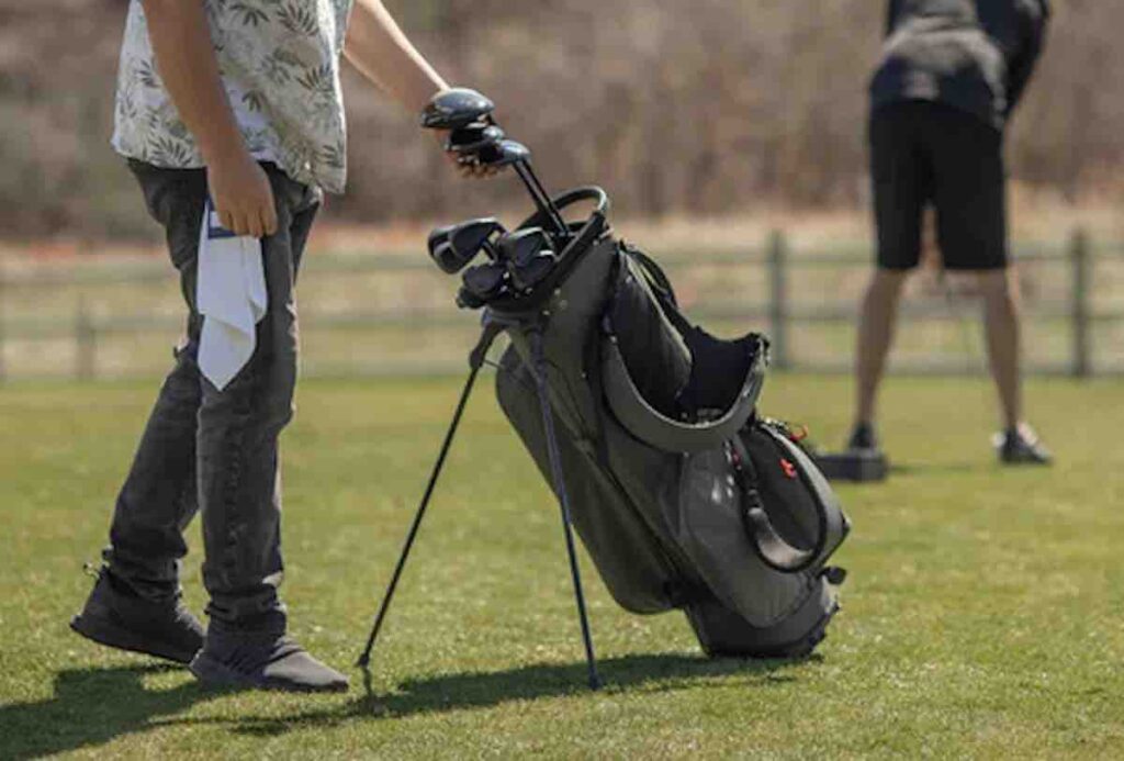 A golfer grabbing a driver from a set of Stix Golf Clubs in a gray golf bag