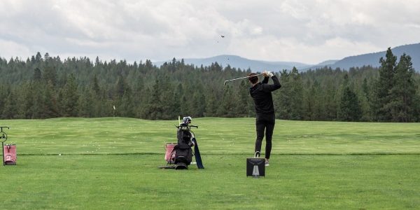 male golfer practicing on the driving range using a golf launch monitor.